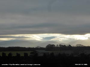 A dark sheet of cloud over Anglesey produced a letter box effect viewing sunny Carneddau on 11 January 2024.