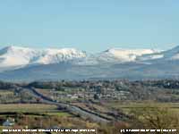 View of Pentre Berw with snow on the mountains.